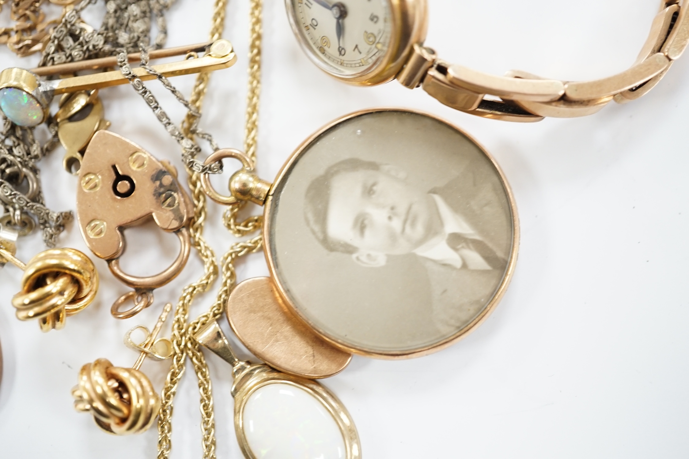 A lady's yellow metal manual wind wrist watch, on a 9ct expanding bracelet, a modern 9ct gold and white opal set pendant, on a 375 chain and other minor jewellery including a pair of 9ct gold knot earrings.